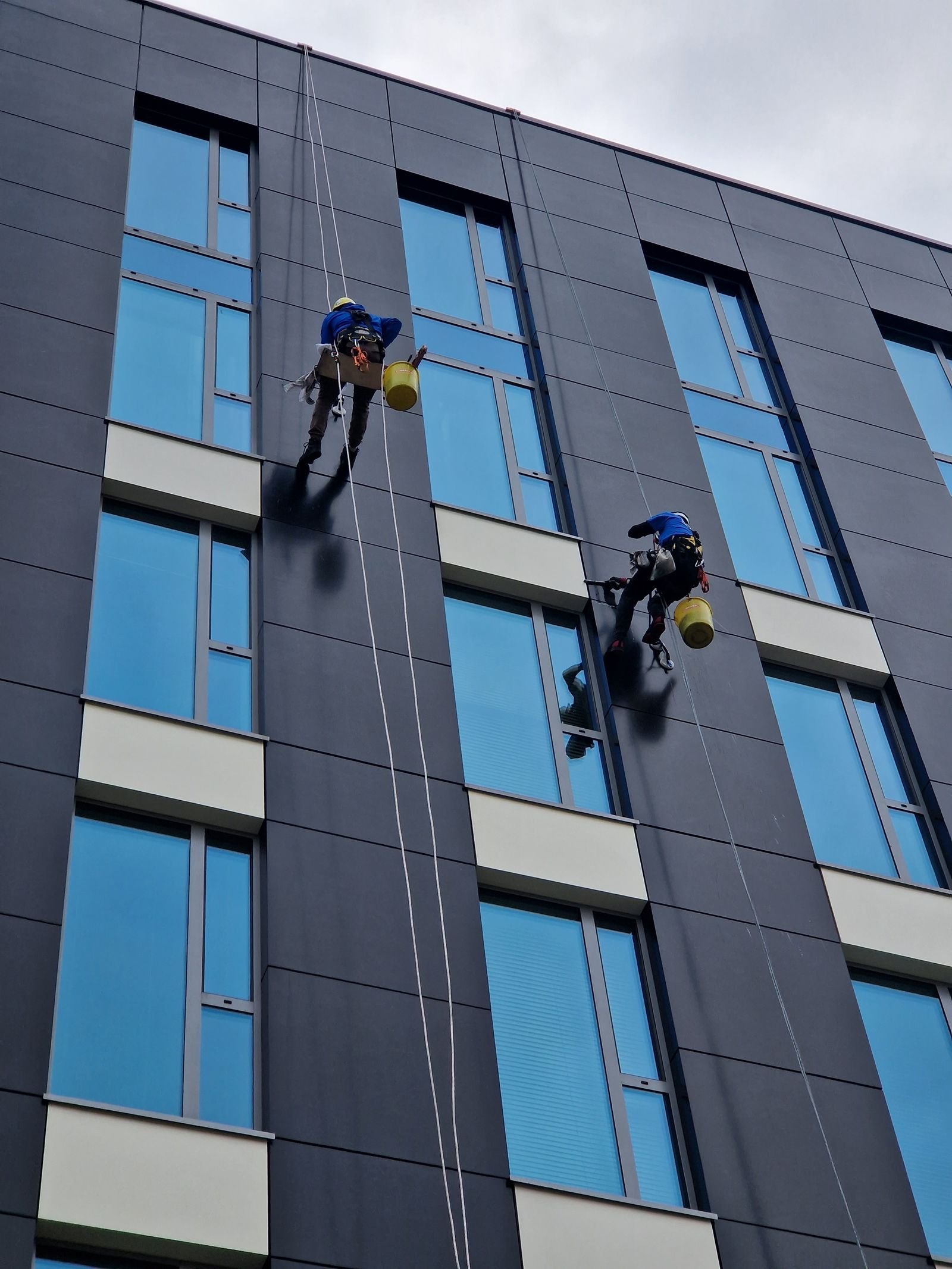 Dos técnicos de acceso por cuerda trabajando en fachada conectados a sus líneas de vida